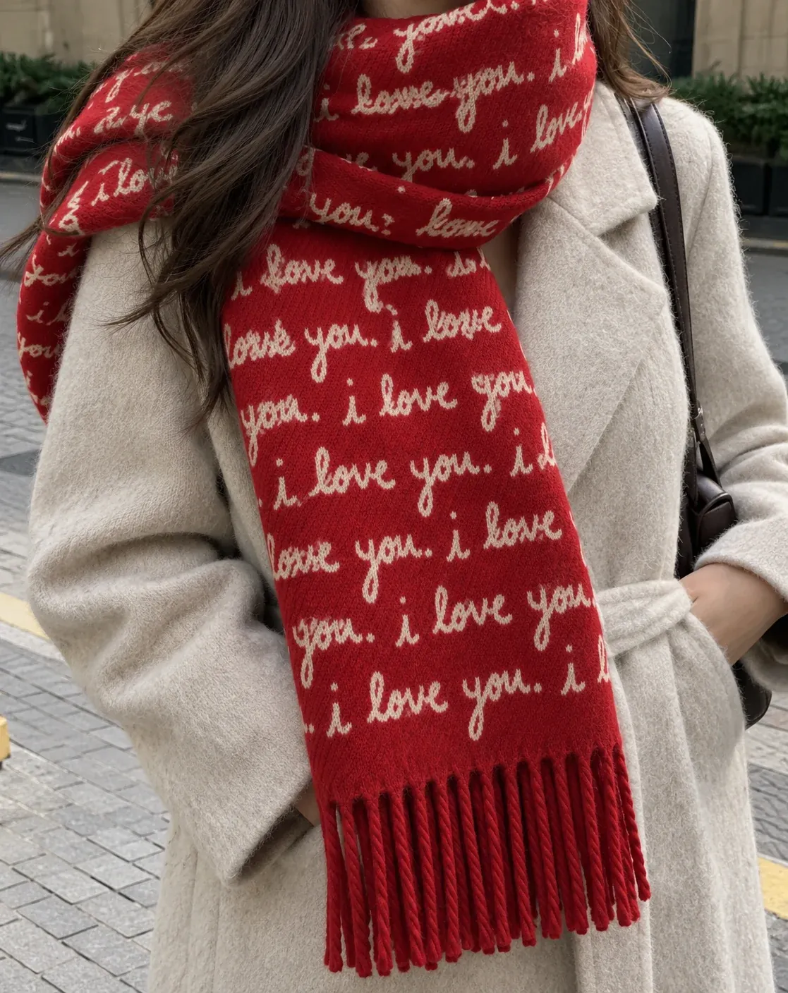 A woman in an oatmeal coat with her hair tucked into the cherry I Love You scarf, cream handwriting all over